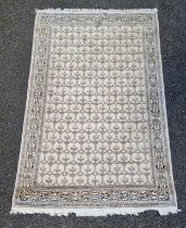 A Kashmiri rug, having repeated decoration to central field, geometric borders on a cream and