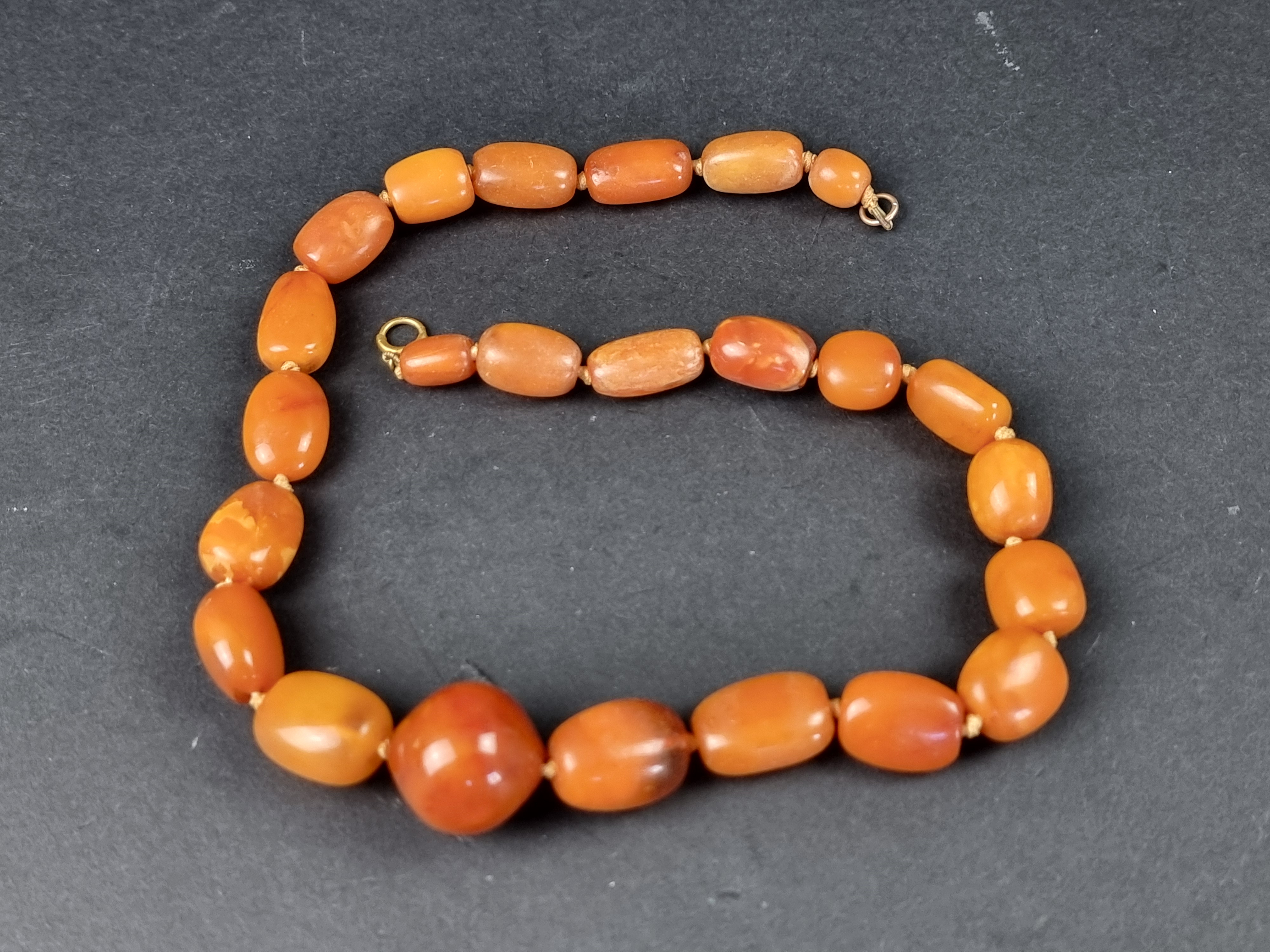 An amber bead necklace, having clasp stamped '375', 46cm long, gross weight 49.1g.