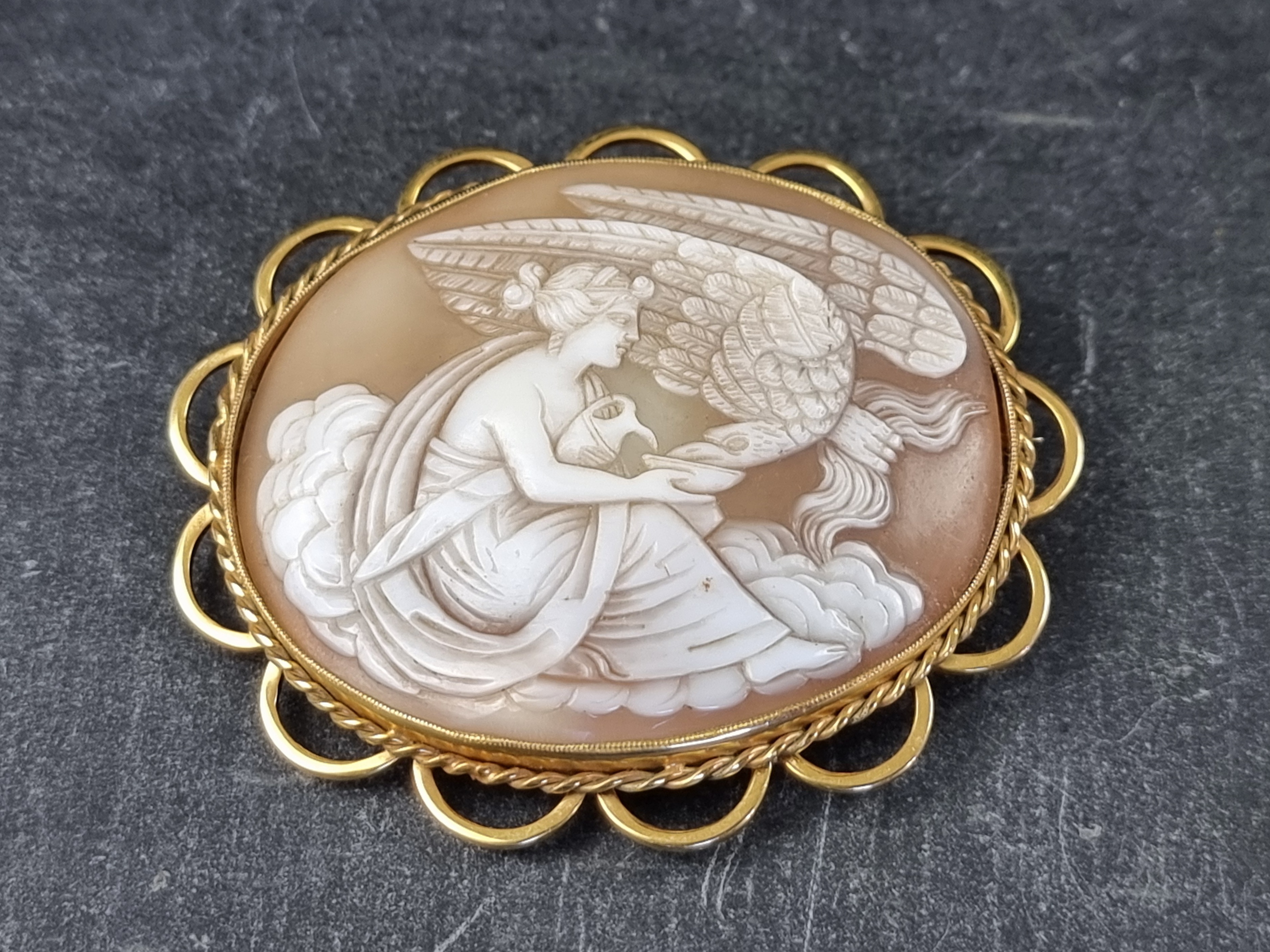 An early 20th century carved shell cameo Leda and The Swan brooch, in a yellow metal mount,