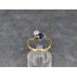 A diamond and sapphire two stone crossover ring, stamped '18ct/Plat', size M 1/2.