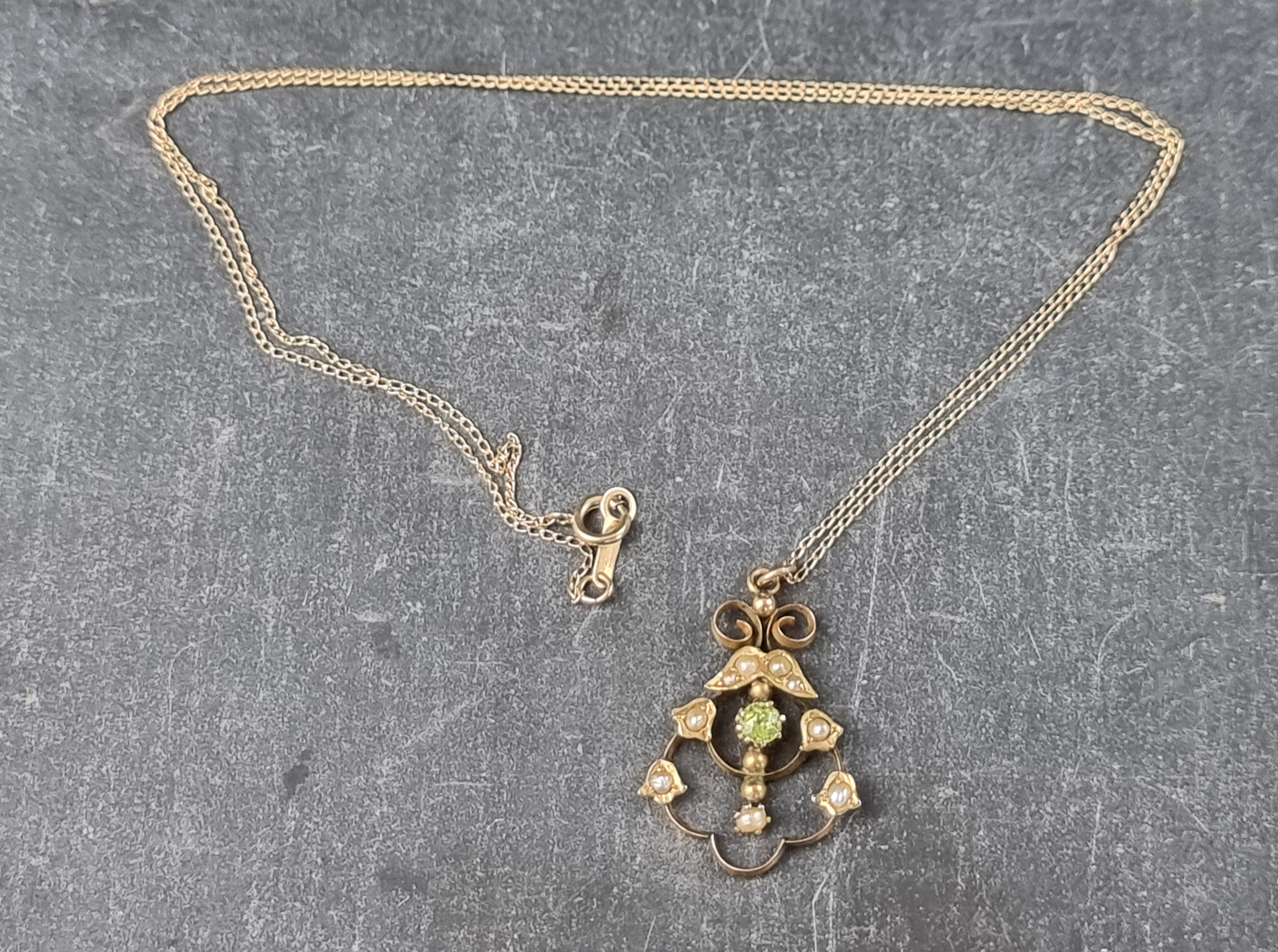 An Edwardian yellow metal, peridot and seed pearl pendant, marked '9ct', 25mm high, on a fine yellow