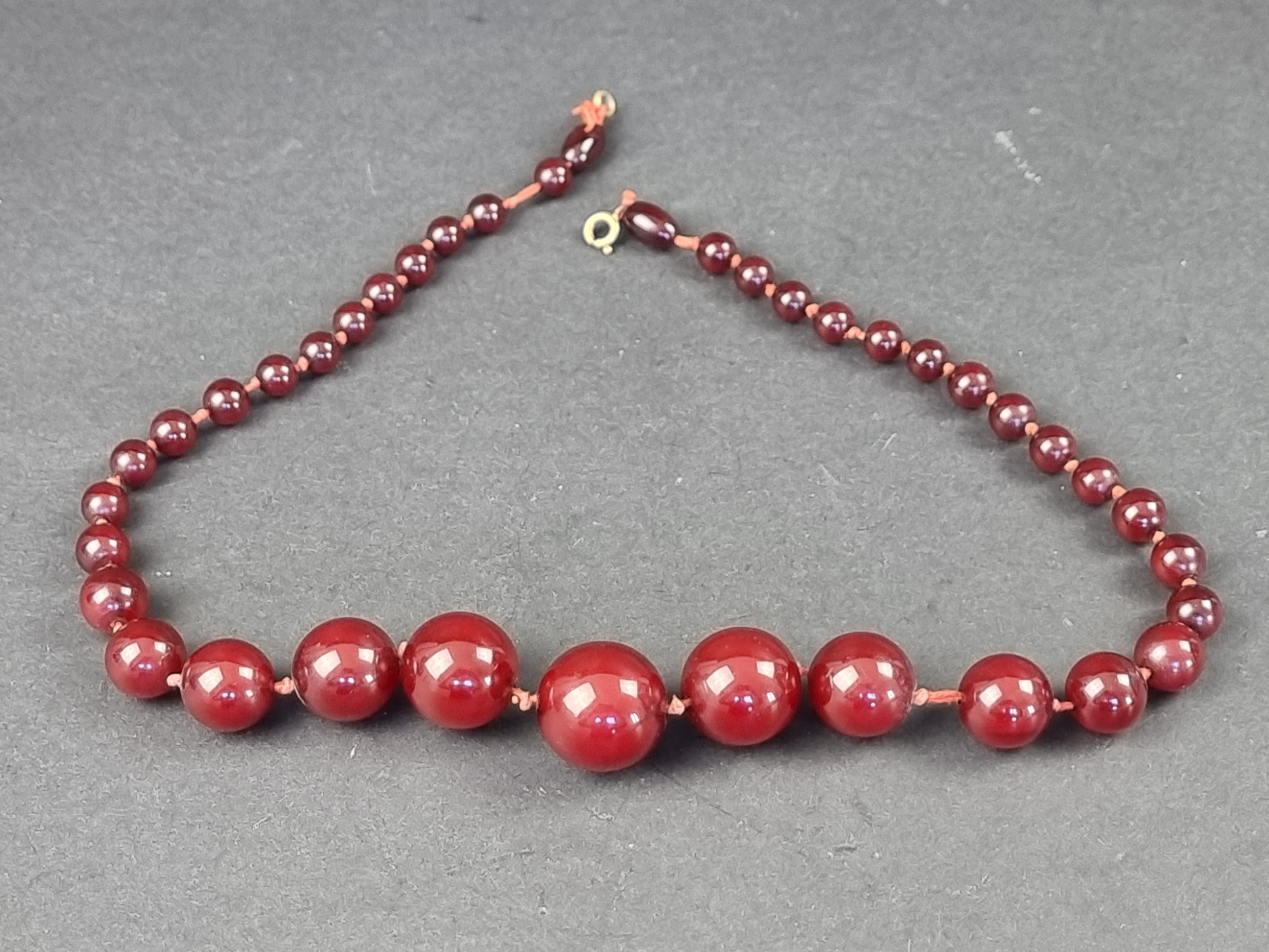 A Bakelite 'cherry amber' bead necklace, the beads 7-21mm diameter, gross weight 46g, 51cm long,