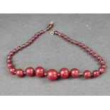 A Bakelite 'cherry amber' bead necklace, the beads 7-21mm diameter, gross weight 46g, 51cm long,