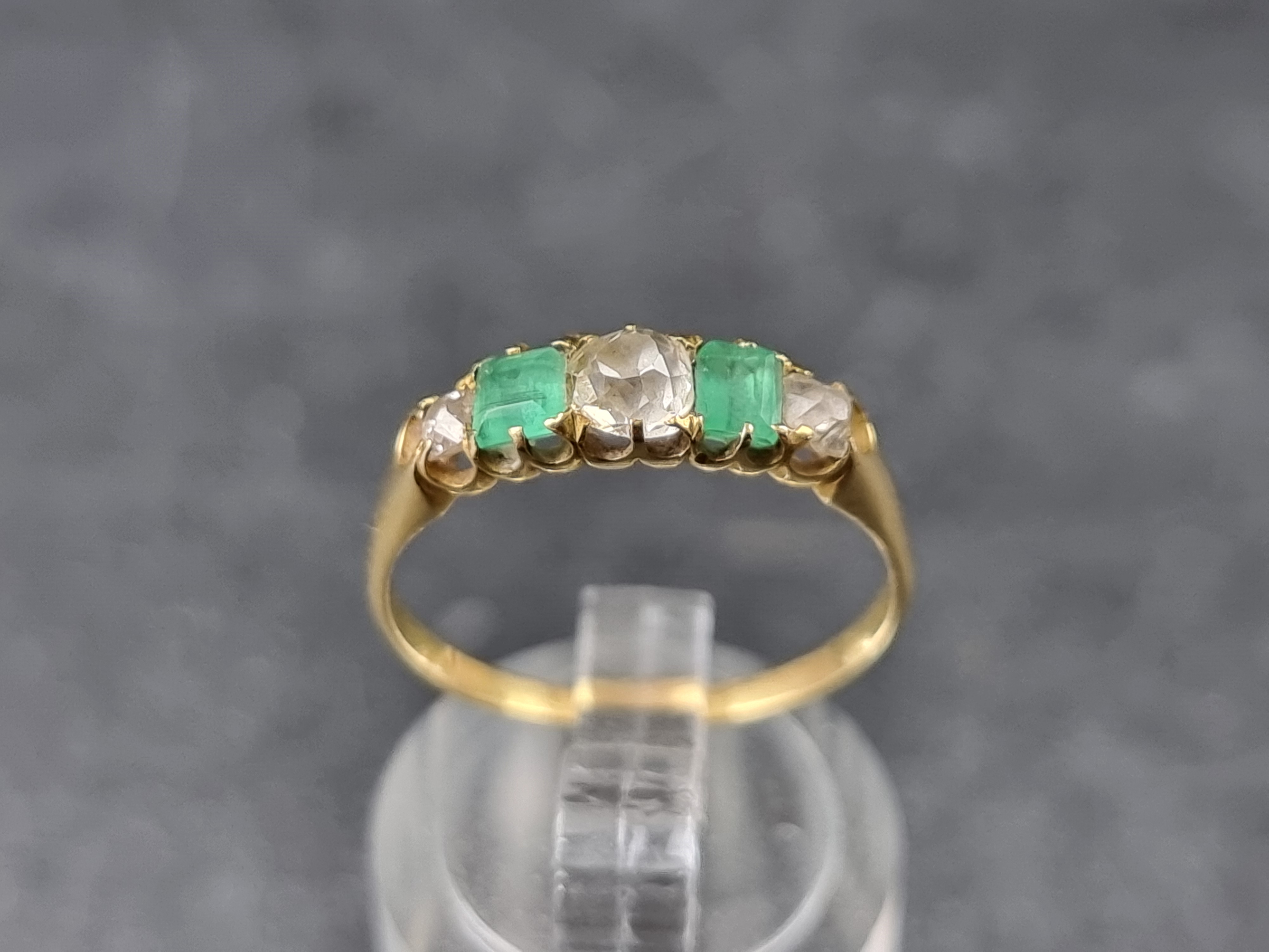 A yellow metal emerald and diamond five stone ring, set three graduated old cut diamonds and two
