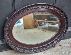 A large stained composition frame oval wall mirror, 99 x 74cm.