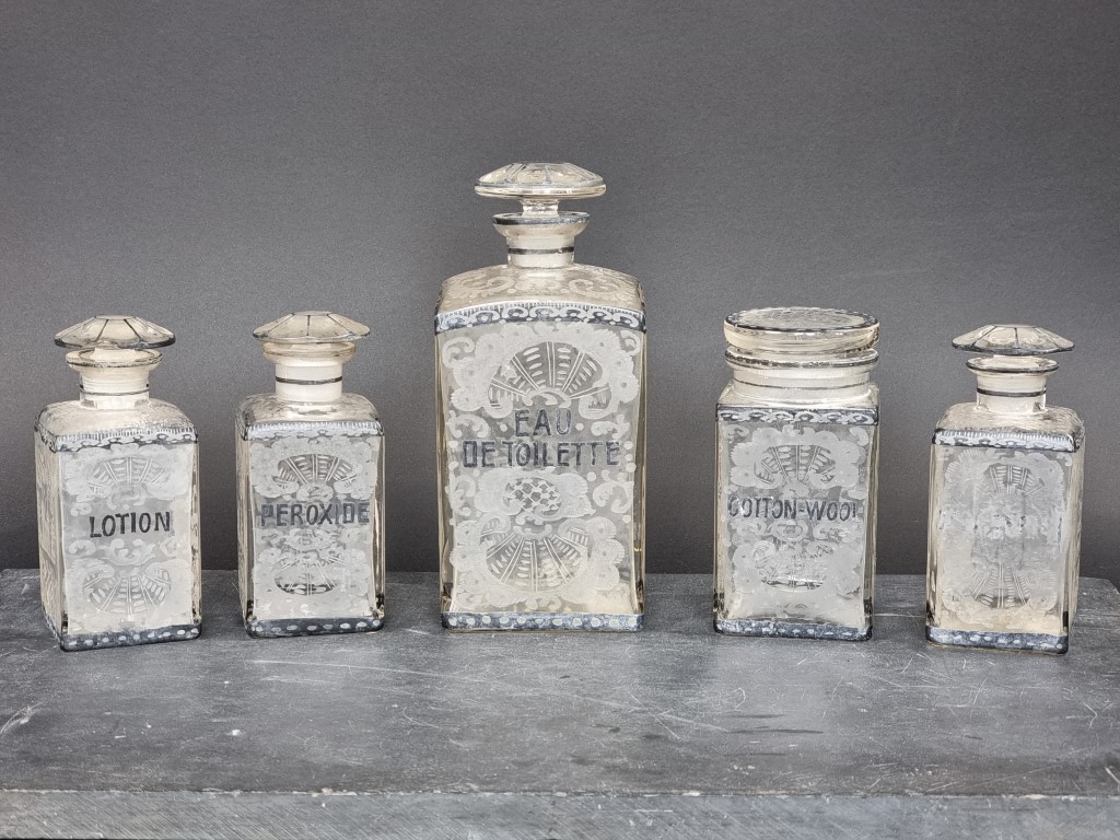 A set of five early 20th century French etched glass toilet jars and stoppers, largest 21cm high. (