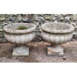 A pair of composition stone urns, 42cm high.