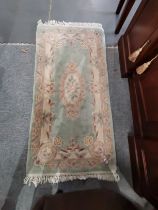 A Chinese woollen rug green ground with beige and pink border