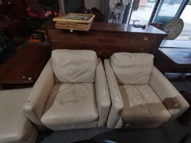 A pair of cream leather arm chairs and matching stool