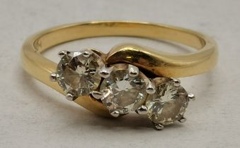 An 18 carat gold diamond three-stone crossover ring