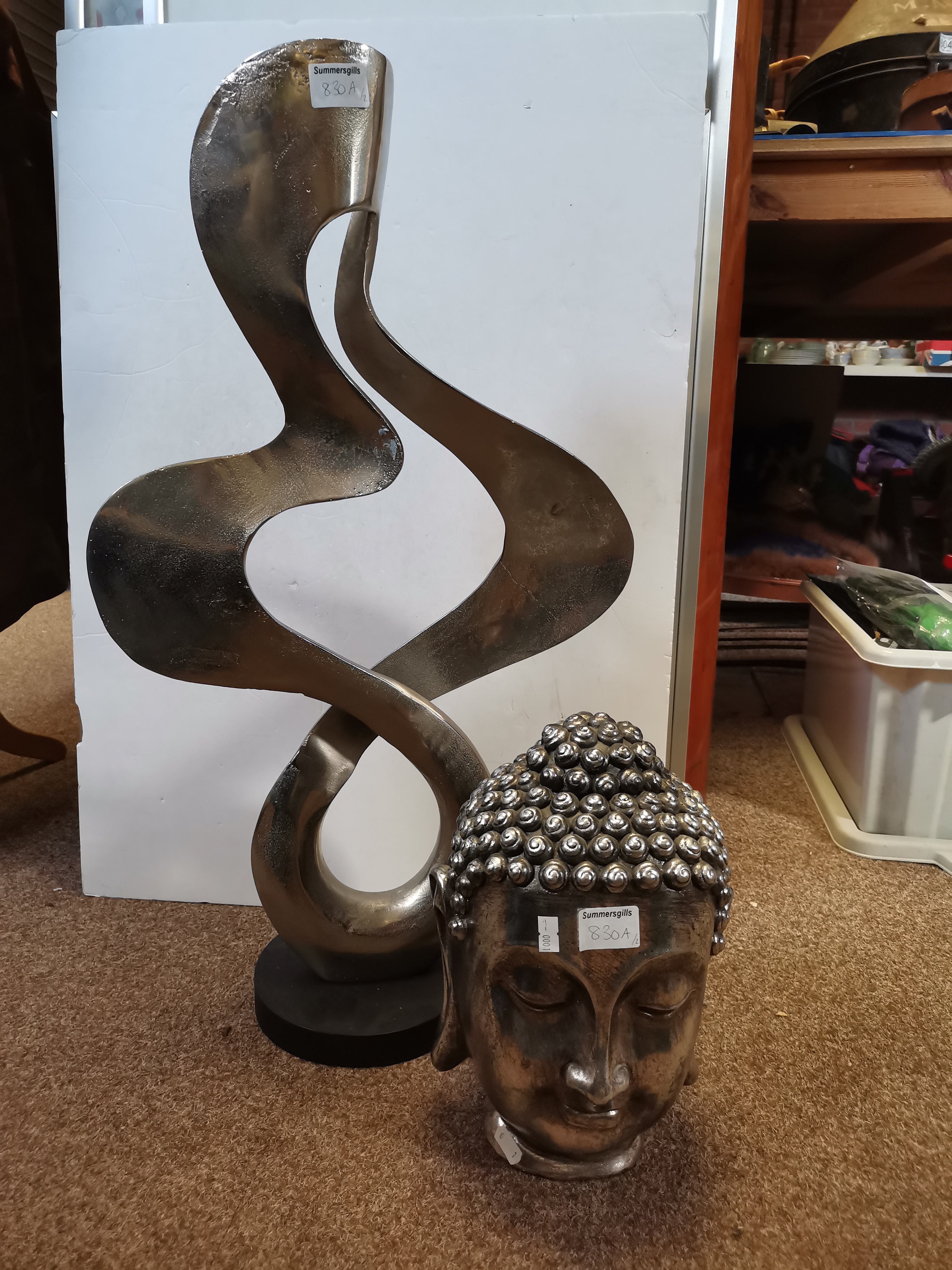 An abstract metal sculpture, and a silvered composite Buddha head