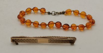 A 9 carat gold tie pin, and an amber bead bracelet