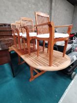 Attractive extending wooden garden dining table with 4 matching carver chairs cream cushions