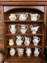 A collection of ceramic cream jugs in a wooden shelf display unit