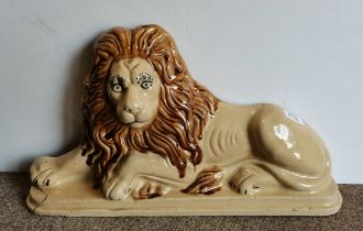 A large pottery figure of a lion door stop lying down with raised head, c.1820s