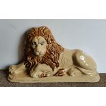 A large pottery figure of a lion door stop lying down with raised head, c.1820s