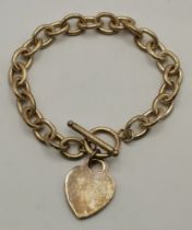 A silver chain link bracelet with ring and T-bar closure, with heart charm