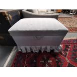 A pale blue upholstered ottoman