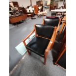 A pair of mid-century Scandinavian style teak and leather armchairs, with black leather seats and ba
