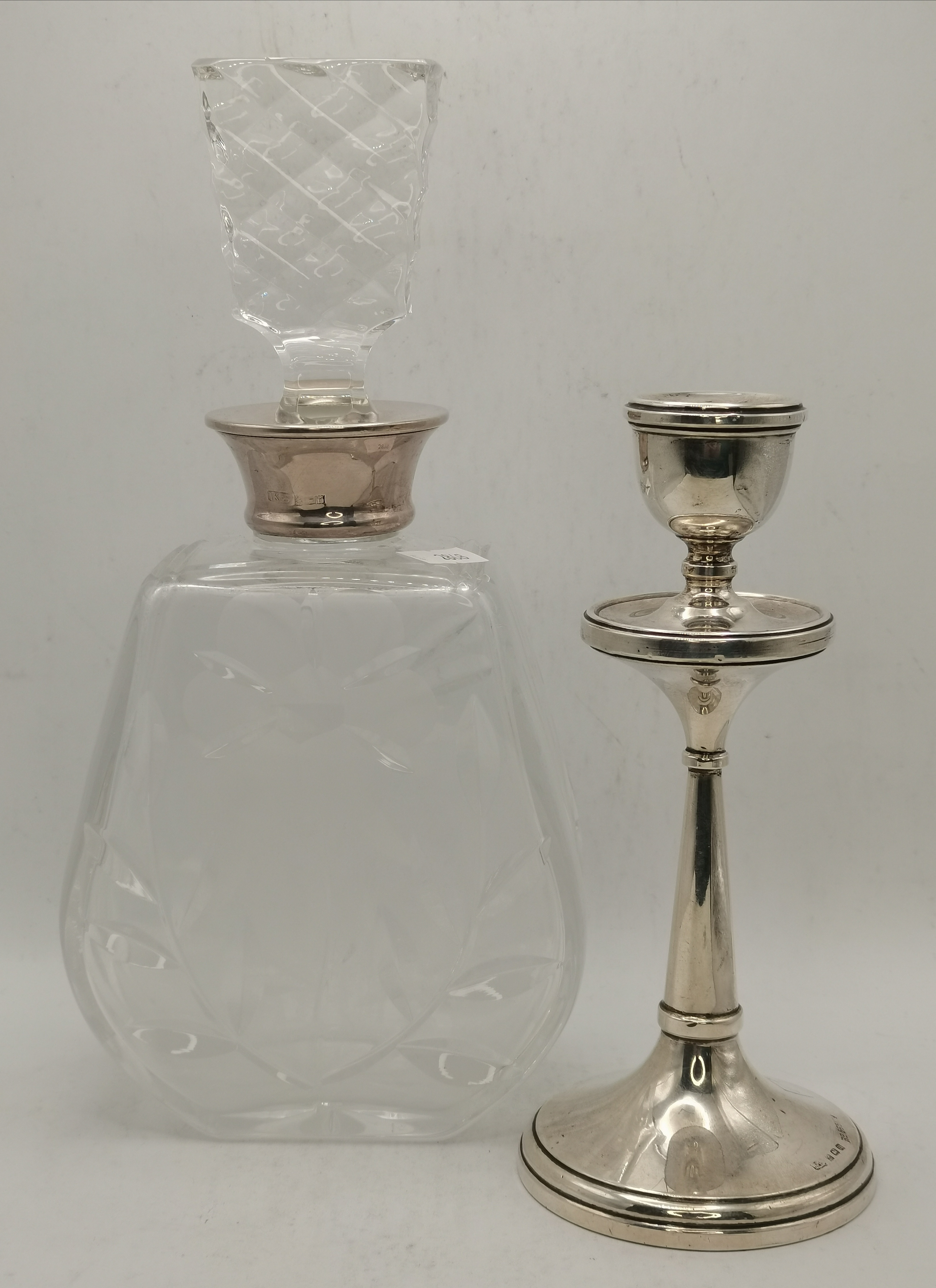 A silver candlestick and silver-mounted glass bottle