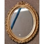 An Antique gilt oval mirror with floral decoration