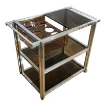 A STYLISH VINTAGE ALUMINIUM AND SMOKED GLASS THREE TIER DRINKS SERVING TROLLEY With six bottle tray,