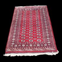 A VINTAGE WOOLLEN BOKHARA RUG With numerous elephant guls contained within running borders on a