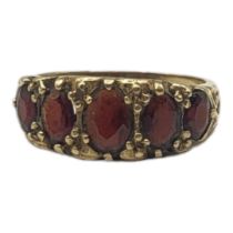 A VINTAGE 9CT GOLD AND GARNET FIVE STONE RING Having a row of oval cut stones in a scrolled
