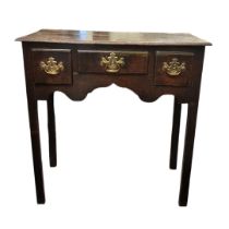 A GEORGIAN OAK LOWBOY The tree drawers fitted with original brass handles above a shaped apron,