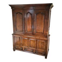 AN 18TH CENTURY SOLID OAK LIVERY CUPBOARD With deep cushion cornice above ogee panelled doors