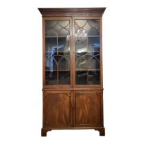 A GEORGIAN MAHOGANY BOOKCASE With blind fret cornice above two gothic glazed doors enclosing