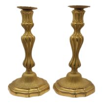 A PAIR OF EARLY 20TH CENTURY BRONZE ORMOLU CANDLESTICKS Having reeded column supports and scrolled