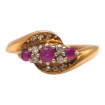 A 9CT GOLD, RUBY AND DIAMOND CROSSOVER RING The central round cut ruby (approx diameter 3mm) flanked