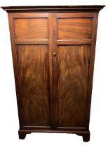 A GEORGE III MAHOGANY TWO DOOR WARDROBE The doors opening to reveal hanging rail the side fitted