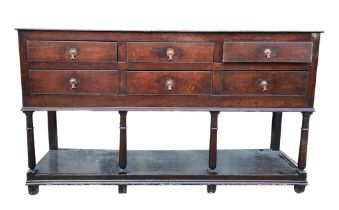 AN 18TH CENTURY OAK DRESSER BASE With six drawers supported on four gun barrel legs joined by a