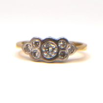 A VINTAGE YELLOW AND WHITE METAL SEVEN STONE DIAMOND RING The central brilliant round cut diamond (