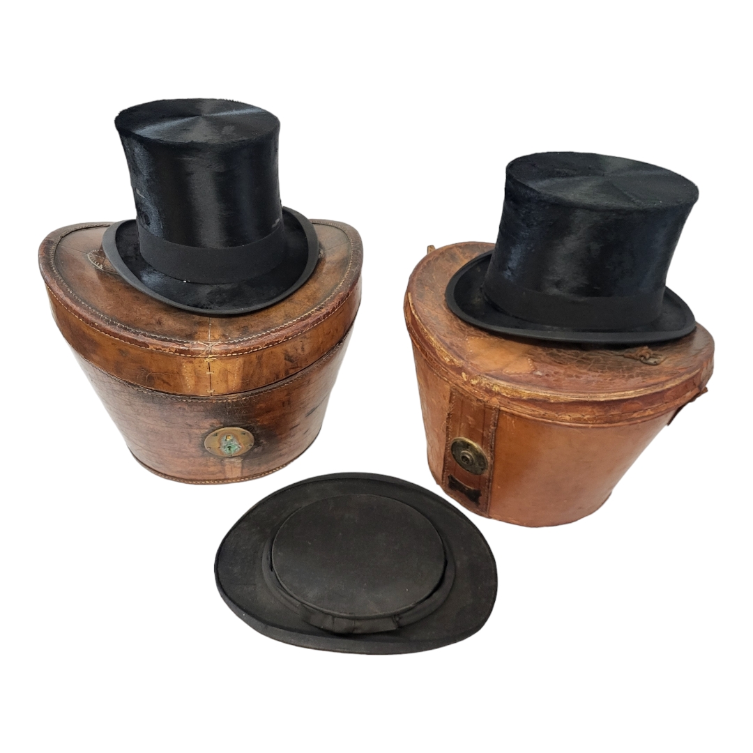 TWO VICTORIAN LEATHER HAT BOXES AND TOP HATS Having a single handle, bearing makers label 'Army