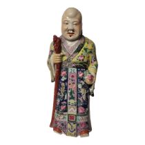 A CHINESE QING DYNASTY FAMILLE ROSE PORCELAIN FIGURE OF AN IMMORTAL Dressed in a flowing robe in