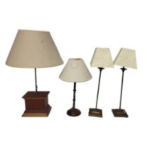 A PAIR OF VINTAGE BRASS TABLE LAMPS Having cream shades and stepped square bases and two wooden
