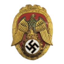 A WWII GERMAN PIONEER OF LABOUR BADGE Oval form with enamel swastika and whale on red enamel ground.