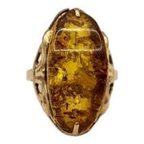 A VINTAGE 14CT GOLD AND AMBER RING The cabochon cut stone set in a pierced design. (size N)