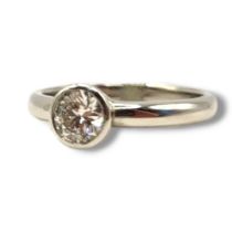 A PLATINUM AND DIAMOND SOLITAIRE RING The single round cut diamond in a rub over mount. (approx 0.