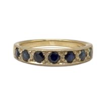 A VINTAGE 18CT GOLD AND SAPPHIRE HALF ETERNITY RING Having a row of round cut stones in a white gold