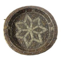 AN ANTIQUE INDO-PERSIAN WOODEN TRIBAL SHALLOW BOWL Centrally embossed with a white metal Arabesque