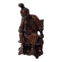 AN EARLY 20TH CENTURY CHINESE HARDWOOD CARVING, A SEATED SCHOLAR WEARING A LONG ROBE On a rustic