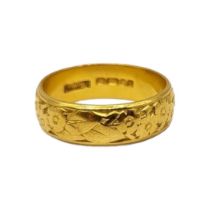 A 22CT GOLD BAND Having floral chased and engraved decoration. (size M½, 5.8g)