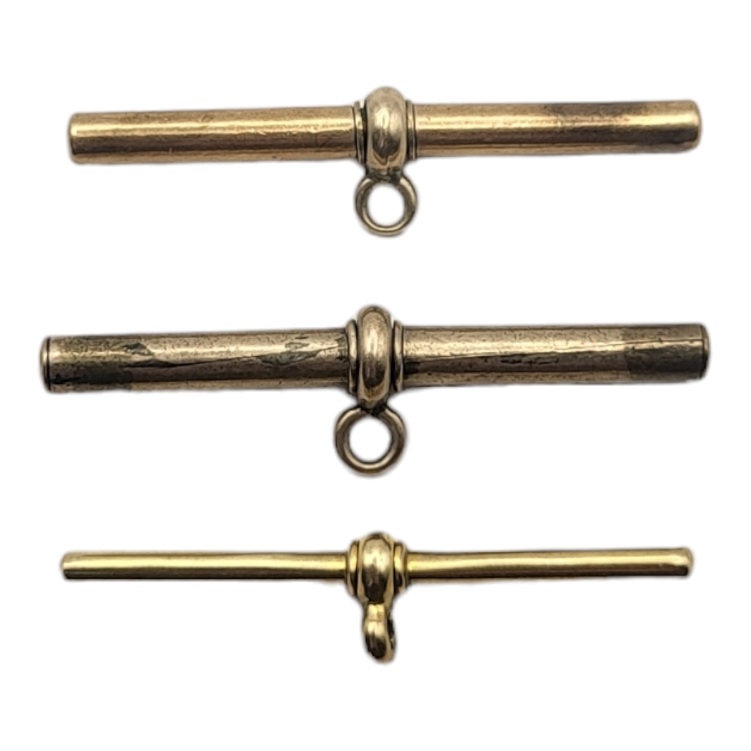 A COLLECTION OF THREE VICTORIAN YELLOW METAL ALBERT WATCH CHAIN 'T' BARS Three graduated sizes.