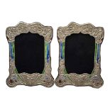 A PAIR OF ART NOUVEAU STYLE SILVER AND ENAMEL PHOTOGRAPH FRAMES Embossed floral design and wooden