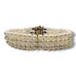A VINTAGE 14CT GOLD AND PEARL BRACELET Three strands of pearls switch square 14ct gold clasp. (