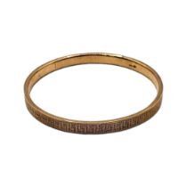 A VINTAGE 9CT GOLD BANGLE Having fine engraved Greek key decoration, inscribed date to interior